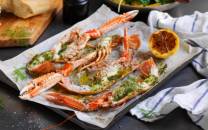 Gratinerte sjøkreps med ramsløksmør servert på et fat med sitronbåt og urter, klar til å nytes.