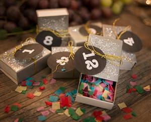 Små gaver med tallkort og konfetti på et bord, klar til nyttårsfeiring.