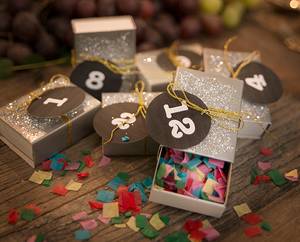 Små gaver med tallkort og konfetti på et bord, klar til nyttårsfeiring.