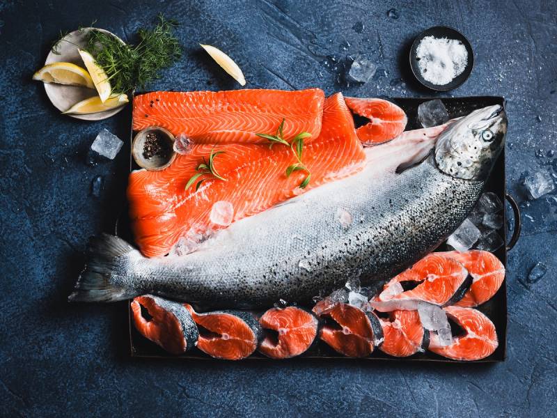 Fersk laks på skjærebrett med sitron, dill og salt, klar for tilberedning