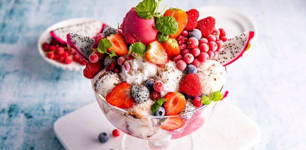 Fargerik iskrem med ulike frukter og bær i en glassbolle, som ser ut til å være en del av en kampanje for iskrem i 2020.