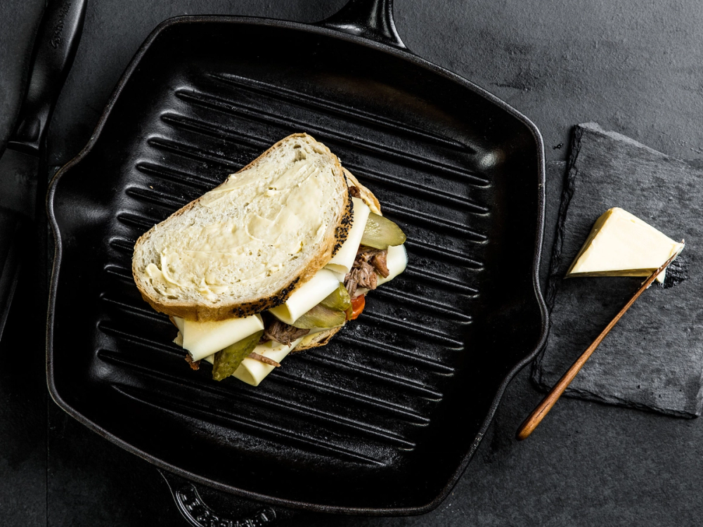 En sandwich med ost og skinke på en grillpanne, klar til å bli stekt eller servert.