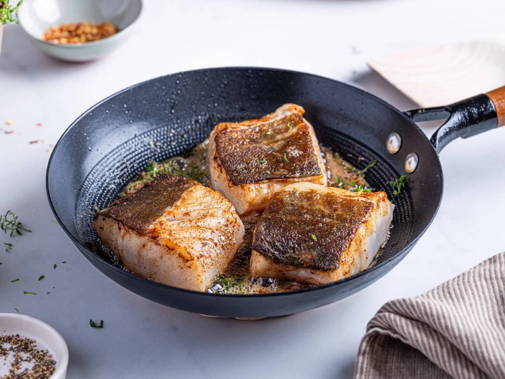 Stekt skrei i en stekepanne med sprø skorpe, klar til servering.