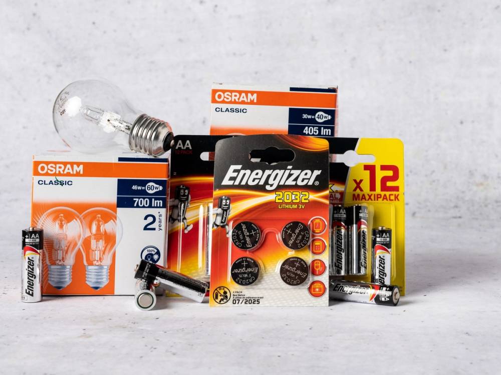 Ulike elektriske lyspærer og batterier fra merker som Osram og Energizer på en hvit bakgrunn.