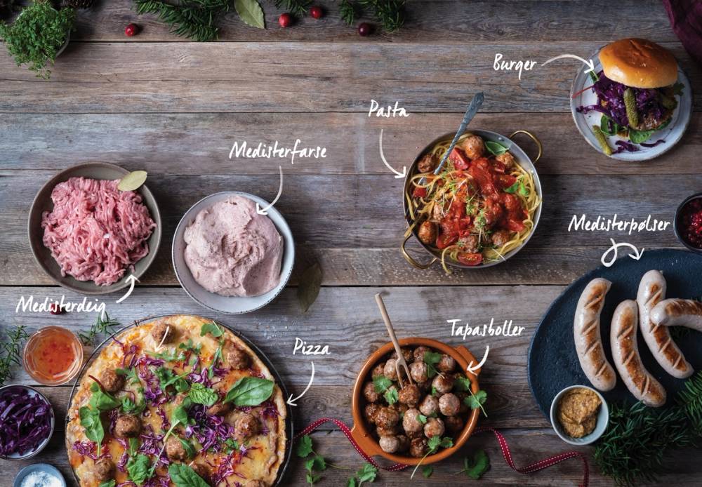 Bilde av medisterdeig, medisterfarse, pølse, pizza, kjøttboller, burger og pølser på et trestykke bord.