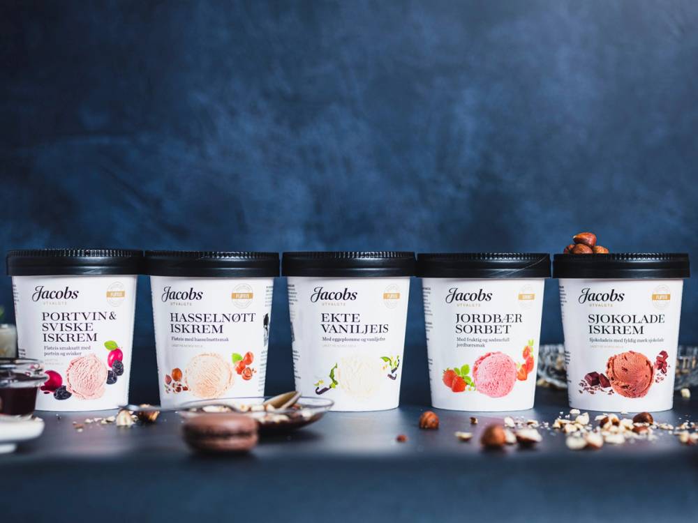 En rekke Jacobs iskrem-vanilje, jordbær og sjokolade-is på en svart bakgrunn med noen spredte sjokoladestykker og småkaker.
