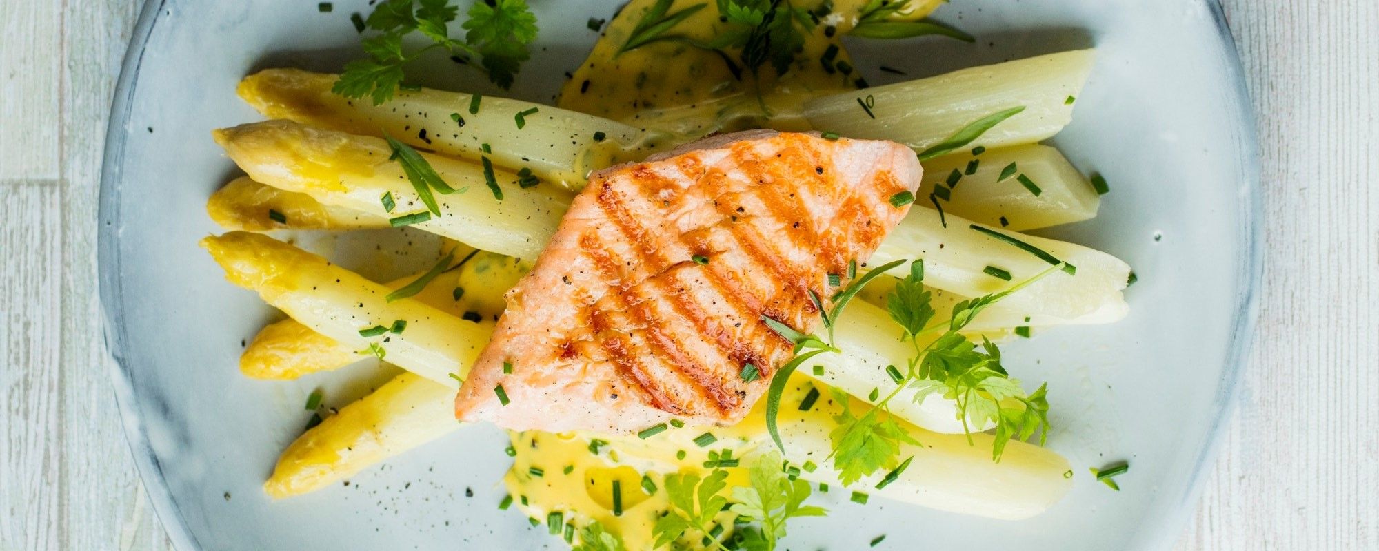 Hvit asparges med en skive laks og frisk dill på en tallerken