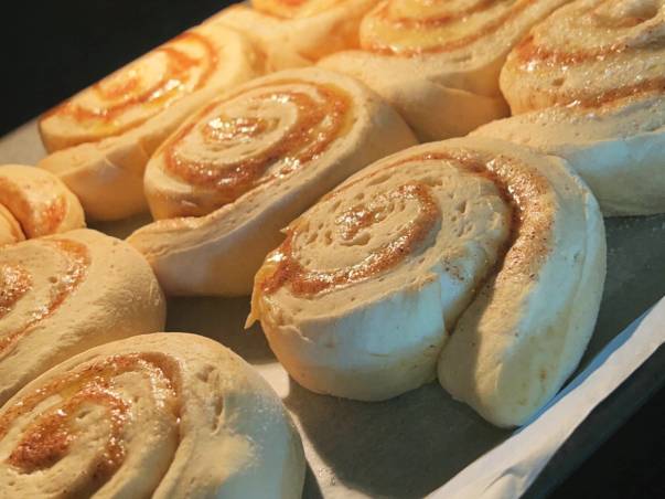 Kanelboller som ligger i en ovn eller på et bakebrett, klare til å bli stekt eller tatt ut av ovnen.