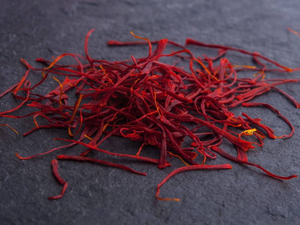Tørkede safrantråder spredt ut på en mørk overflate