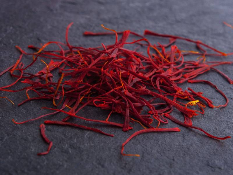 Tørkede safrantråder spredt ut på en mørk overflate
