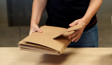 Person som holder en pappeske med flere lag av papp, klar til å åpne eller pakke ut innholdet.