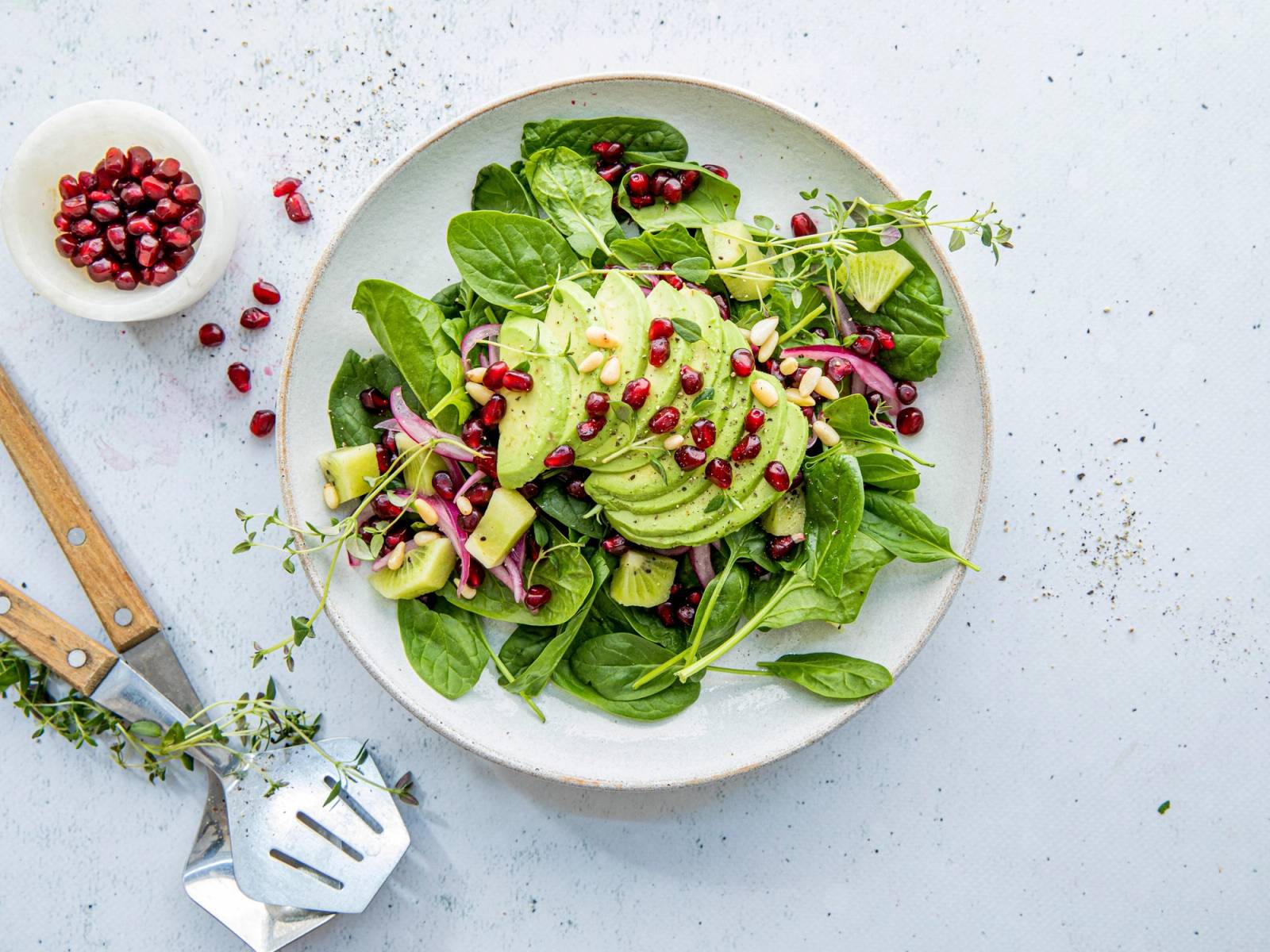En frisk salat med babyspinat, avokadobiter og kiwi på en hvit tallerken