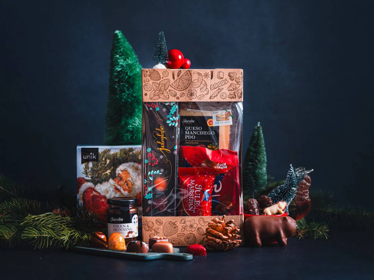 Julegaver og julepynt med små trær og dekorasjoner mot en mørk bakgrunn.