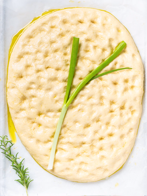 Focaccia med blomsterformede grønne løk som pynt, ser ut som en blomsterfocaccia.