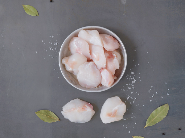 Skåldede og rensede skreikjaker i en hvit bolle, omgitt av noen få laurbærblader på en mørk bakgrunn.