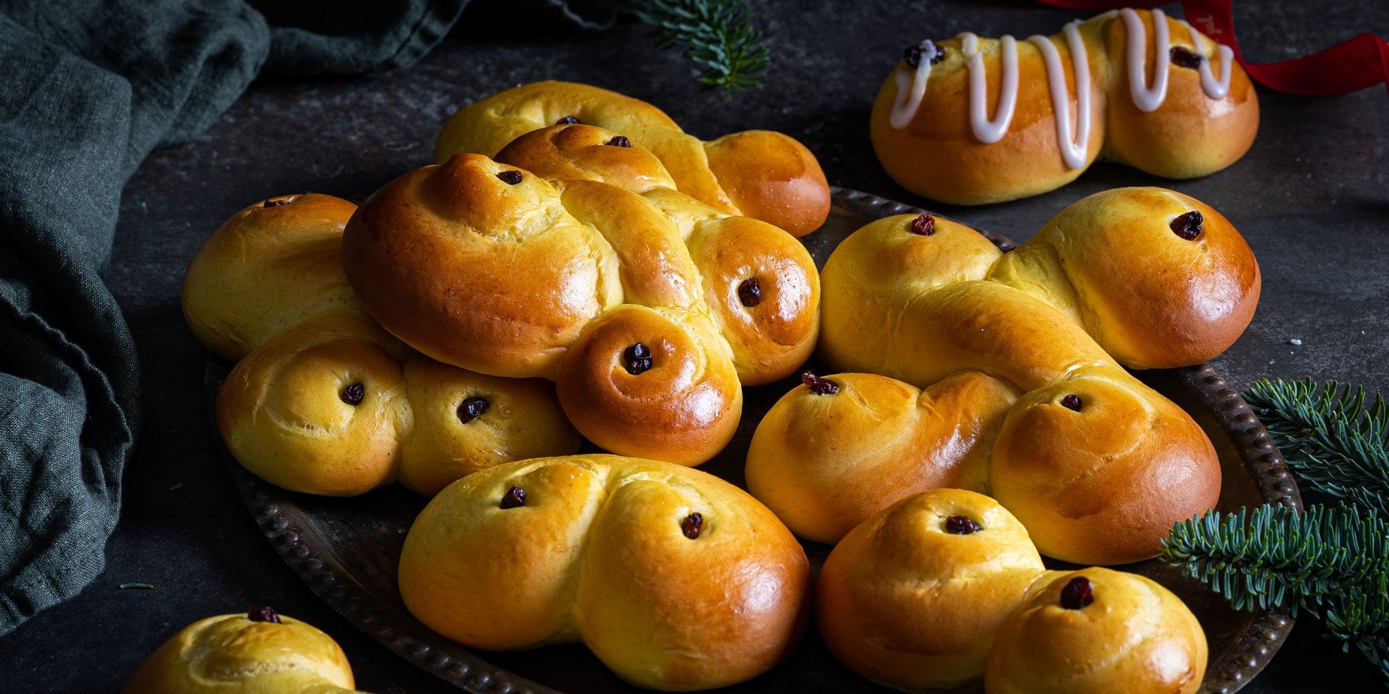 Lussekatter formet som små katter og med rosiner som øyne, ligger på et fat.