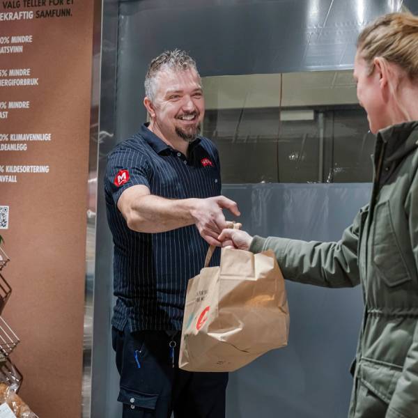 MENY-ansatt overleverer en Too Good To Go-pose til kunde.