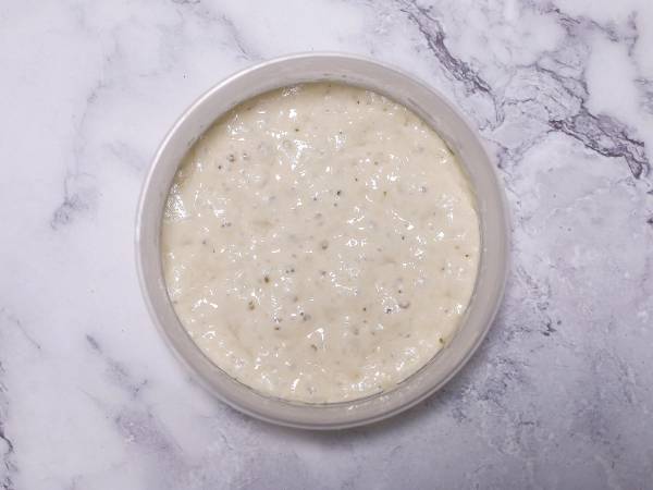 En bolle med hvit, jevnt blandet poolish-deig på en marmorgulvet.