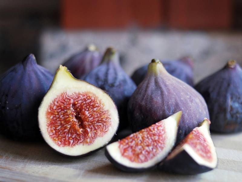 Ferske fiken med en dyp rød innside og lilla ytre, plassert på en treflate.