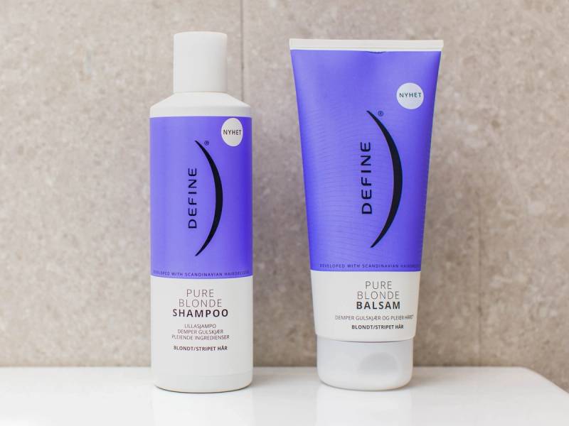 To hårpleieprodukter med blå og hvit emballasje står på en lys bakgrunn, en flaske og en tube av merkevaren Define.