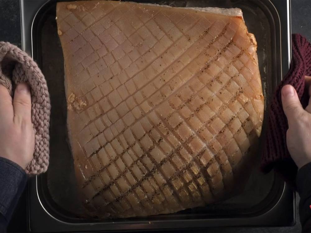 Stekt ribbe med sprø svor på en svart stekeplate, klar til servering.