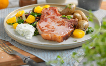 Sommerkoteletter med grønnkål, sopp og poteter på en tallerken, med en skål med smør og en annen med sopp i bakgrunnen.