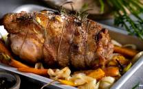 En klassisk lammestek servert med ovnsstekte gulrøtter og hvitløk på et serveringsfat.