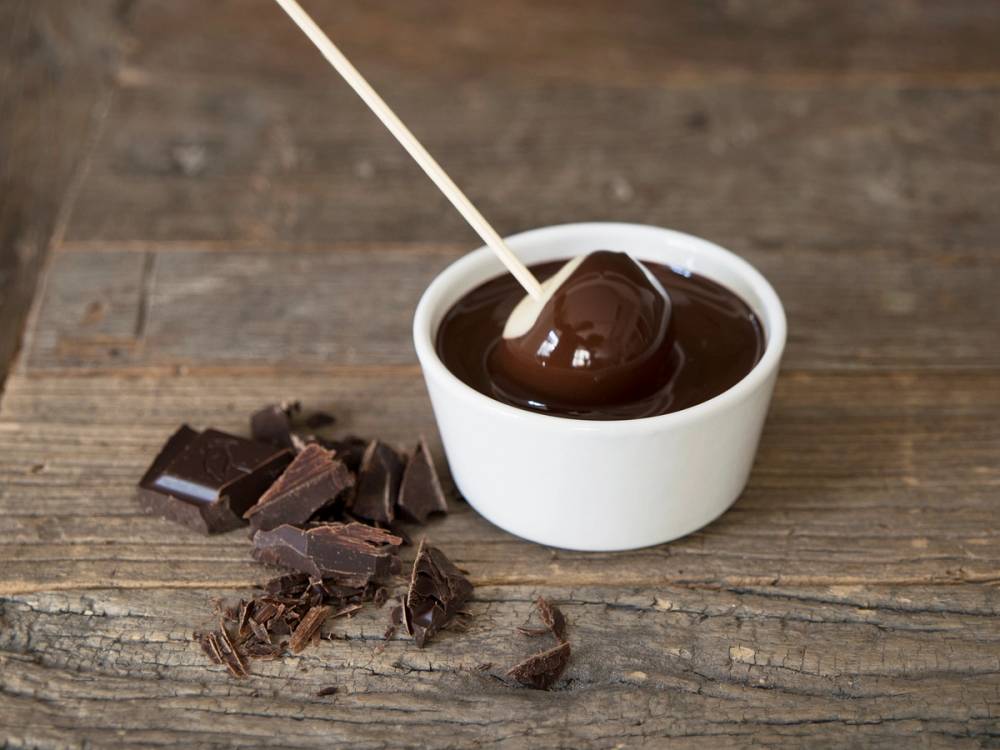 Hjemmelaget marsipan i en hvit skål med noen brutt biter av sjokolade ved siden av på et treverkbord.