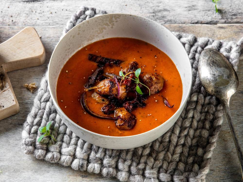 Meksikansk suppe med kjøttbiter og krydder i en hvit bolle på et trebord