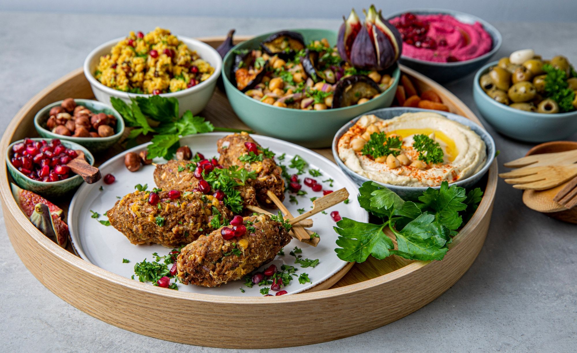 Varierte retter og småretter på et rundt serveringsfat med grønnsaker og dipper, inkludert kålrotstappe og oliven.