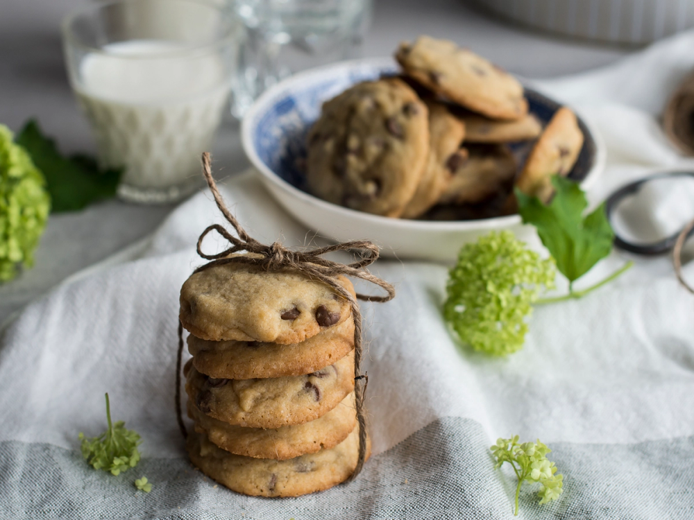 En stabel med sjokoladekjeks bundet med en snor foran en skål med flere kjeks i bakgrunnen.