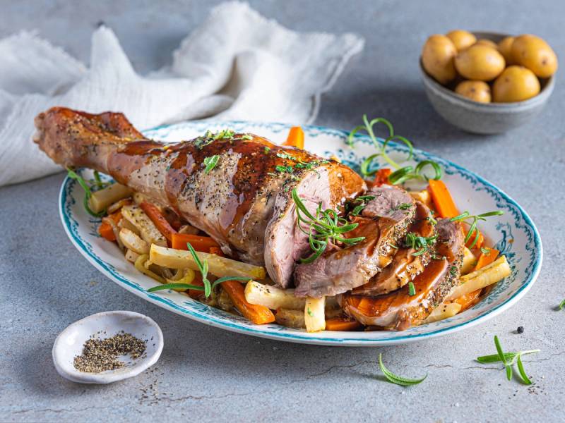 Lammekjøtt med grønnsaker og saus på et serveringsfat, med en skål med egg og en liten skål med krydder i bakgrunnen.