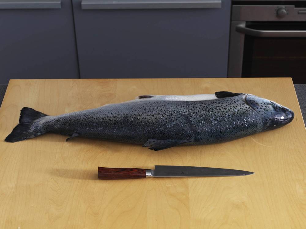 En hel laksefilet ligger på et kjøkkenbord med en kniv foran den.