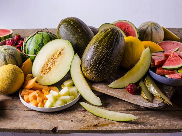 Et utvalg av ulike typer meloner, inkludert vannmelon, honningmelon og cantaloupe, på et bord.