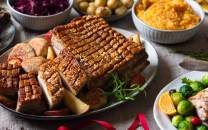 Et julebord med ribbe, medisterkaker og tilbehør som rosenkål og appelsin, omgitt av ulike retter og garnityr.