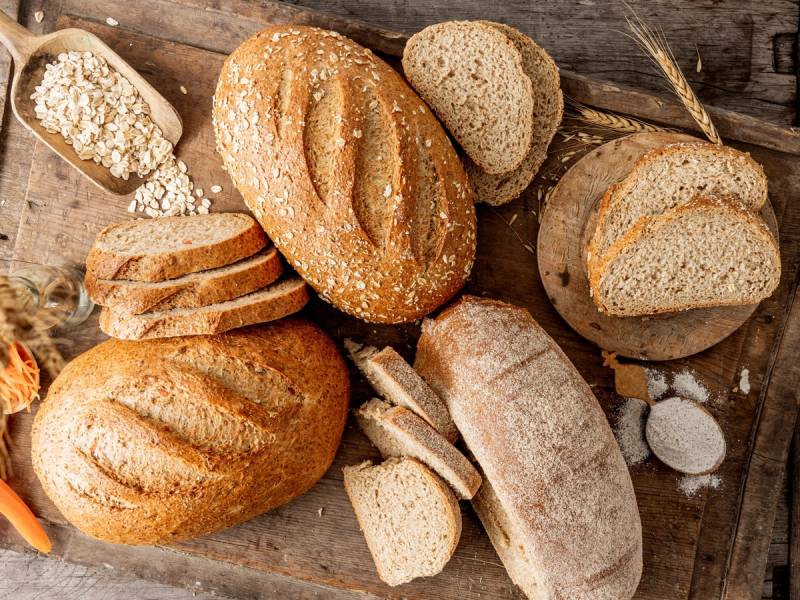 Ulike typer brød og baguetter på et trebord, klare til å bli servert eller spist.