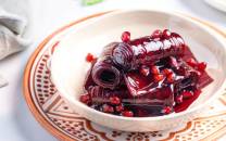 En skål med lavashak, en tradisjonell tyrkisk fruktgelé med granateple, ser ut til å være fylt med granateplefrø og sirup, plassert på et dekorativt fat.