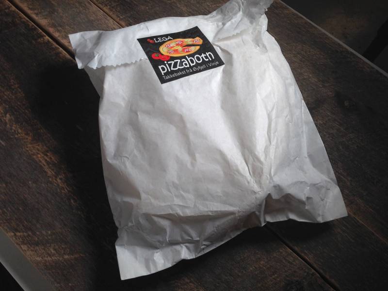 En pizzabunn pakket inn i hvit papir med en logo som sier 'Lega pizza botn'.