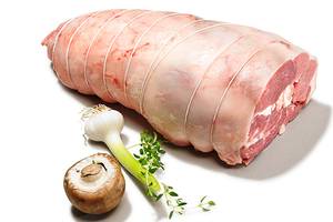 Lammestek som er surret inn i kjøkkenstrimler, med hvitløk, sopp og urter ved siden av.