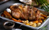 En klassisk lammestek servert på en tallerken med rotgrønnsaker og hvitløk, pyntet med urter.