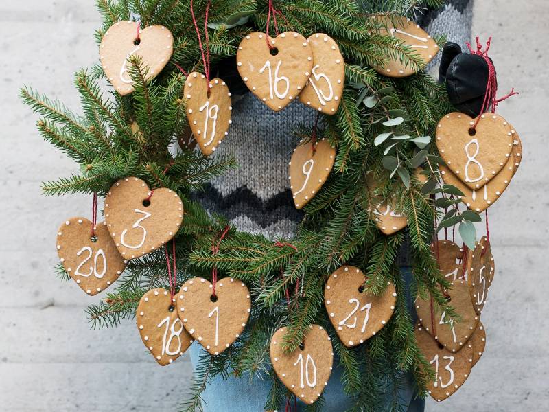 Pepperkakekalender med hjerteformede pepperkaker med tall, hengende på en julegran