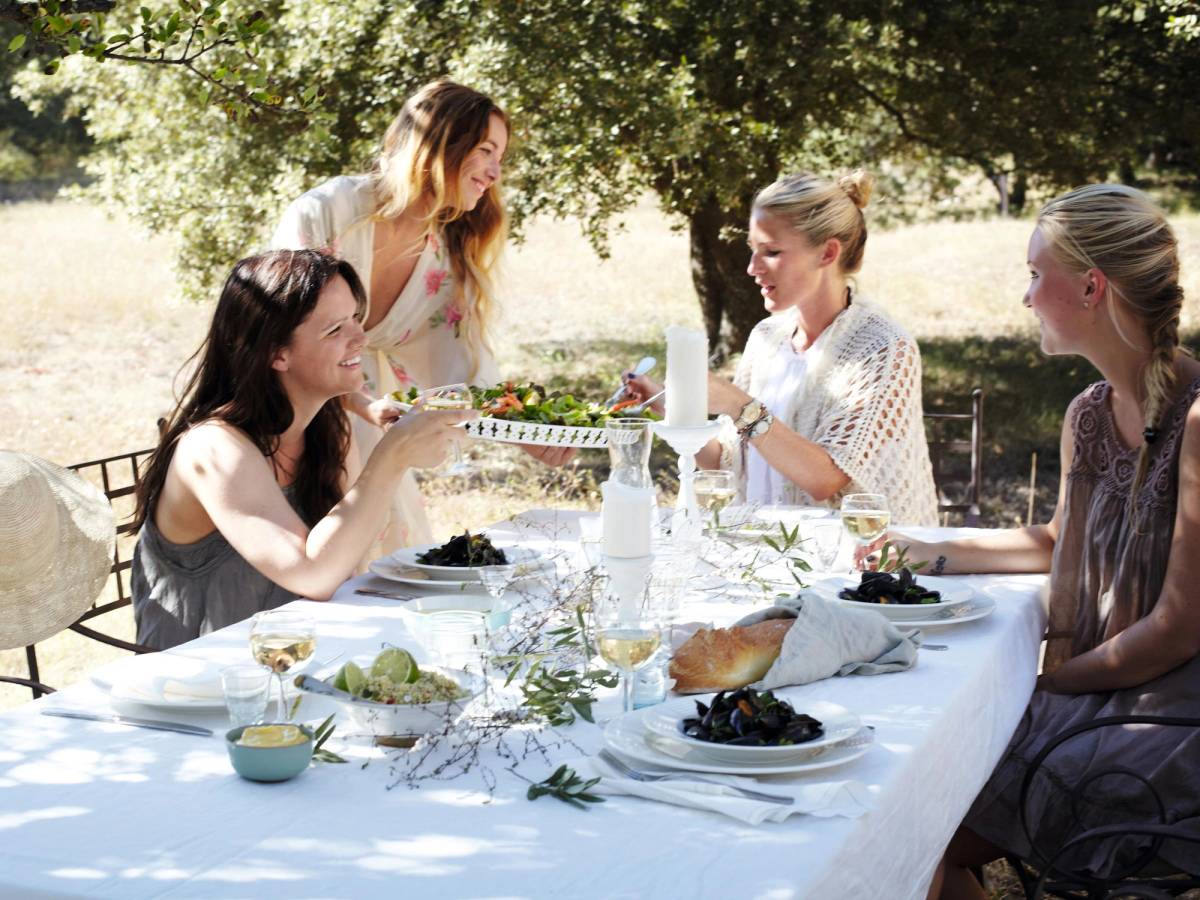 En vennegjeng rundt et dekket bord i hagen.