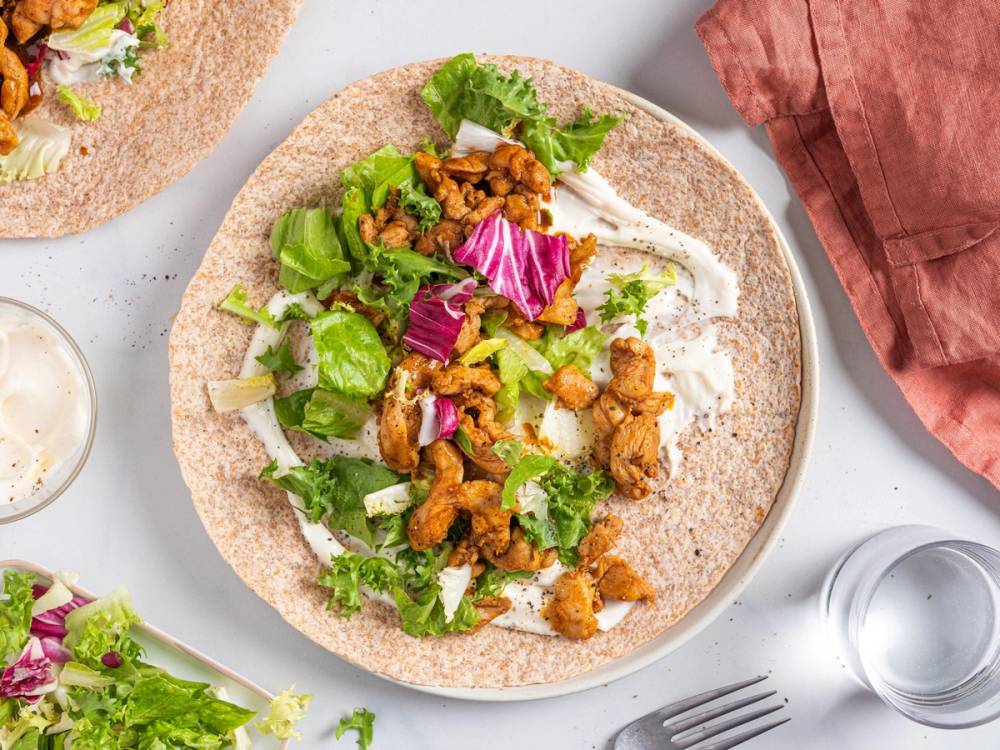 Wraps med strimlet kylling, salat og grønnsaker på en tallerken