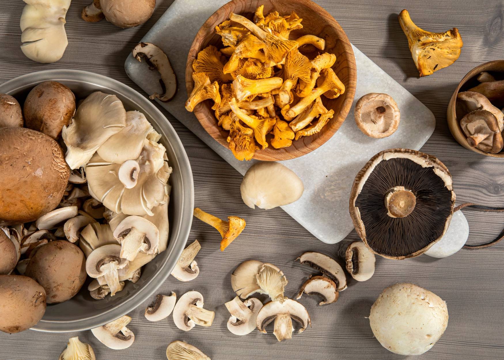 Ulike sopp sortert i skåler og på bordet, inkludert champignon, kantareller og shiitakesopp.