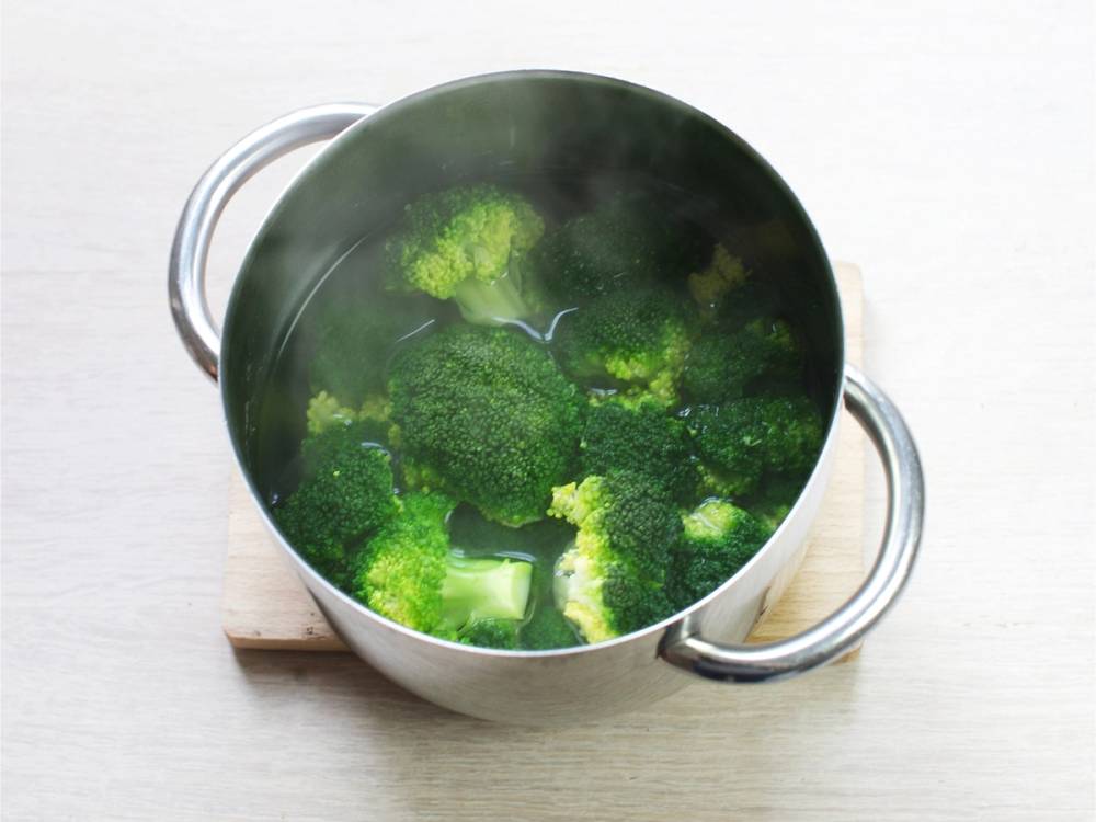 Brokkoli kokes i en stor kjele med vann på et kjøkkenbord
