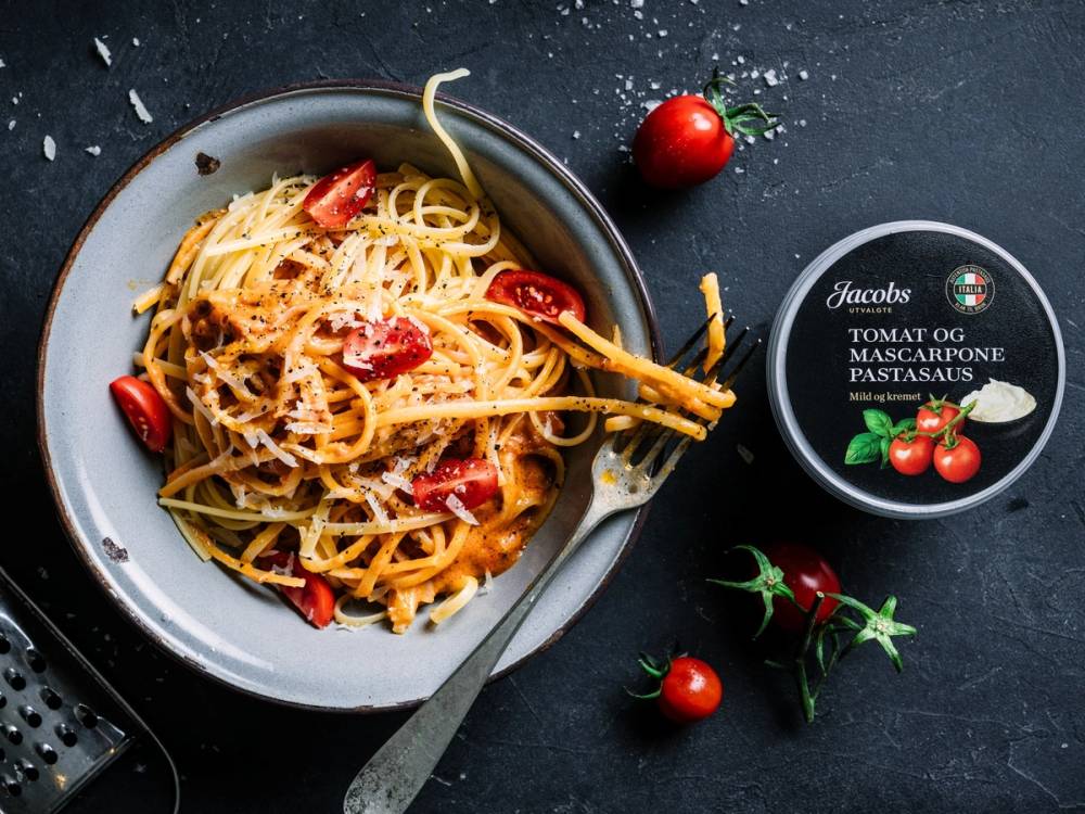 Pasta med tomatsaus og cherrytomater på en tallerken, med en boks Jacobs pastasaus ved siden av.
