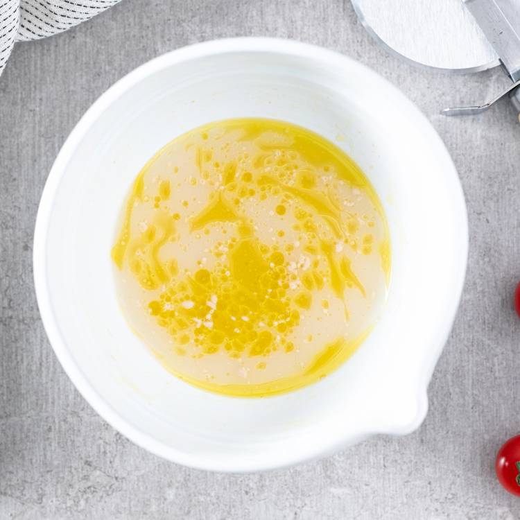 Pisket pizzadeig i en hvit bolle på et kjøkkenbord