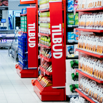 Hyller med ulike tilbudsprodukter i en butikk, med tydelige TILBUD-skilt på sidene, i en butikk med godt utvalg av varer.