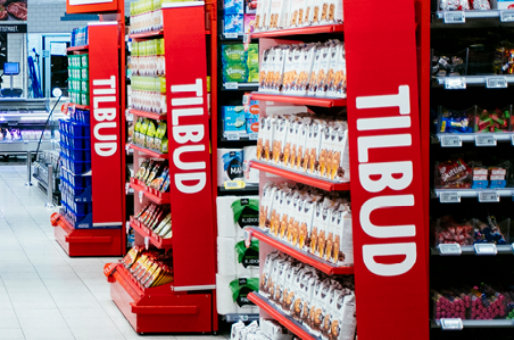 Hyller med ulike tilbudsprodukter i en butikk, med tydelige TILBUD-skilt på sidene, i en butikk med godt utvalg av varer.