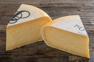 To stykker ost med gul farge og hvit skorpetekst, plassert på en treoverflate.